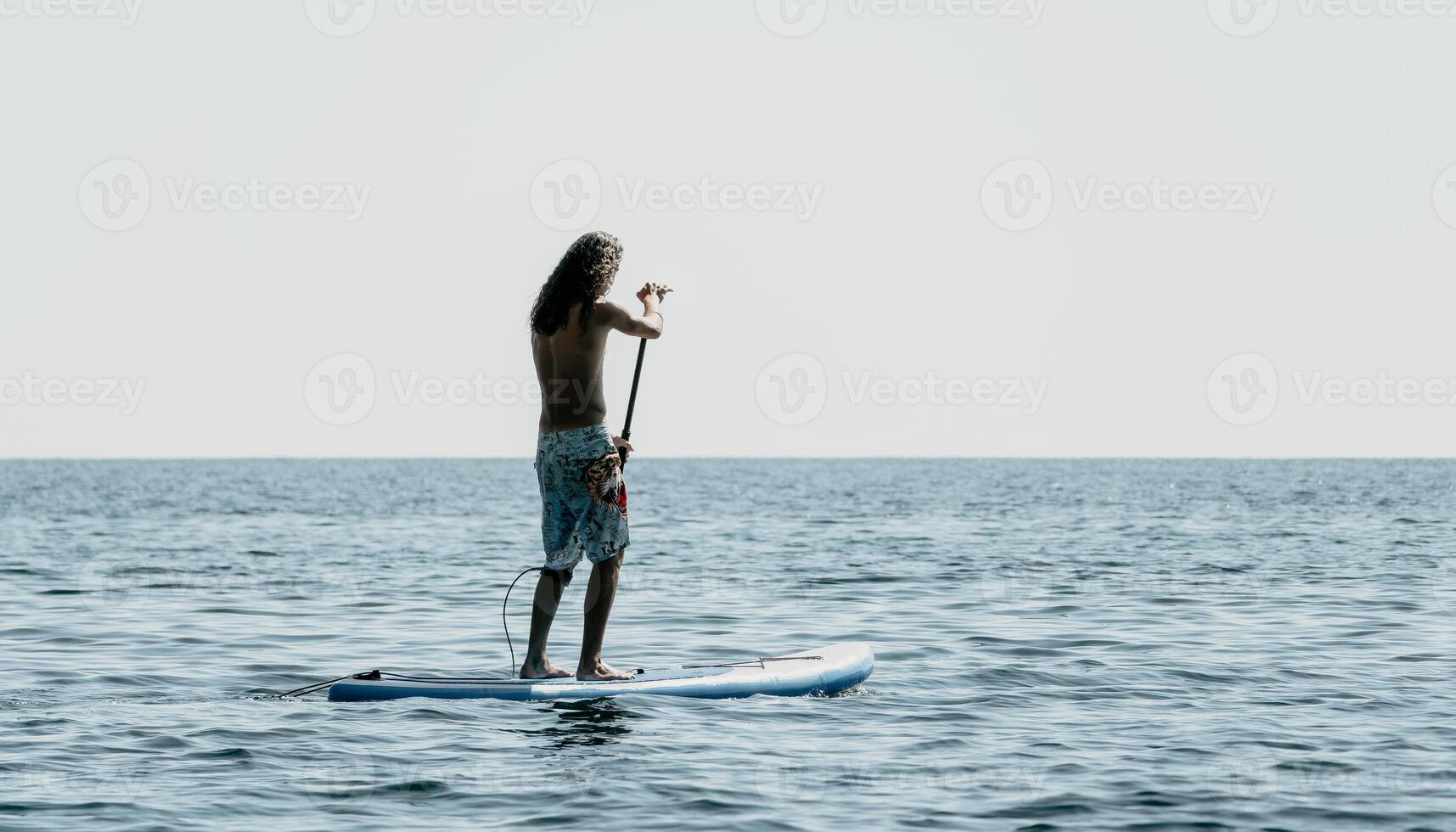 Man Sup Sea. Strong athletic man learns to paddle sup standing on board in open sea ocean on sunny day. Summer holiday vacation and travel concept. Aerial view. Slow motion photo