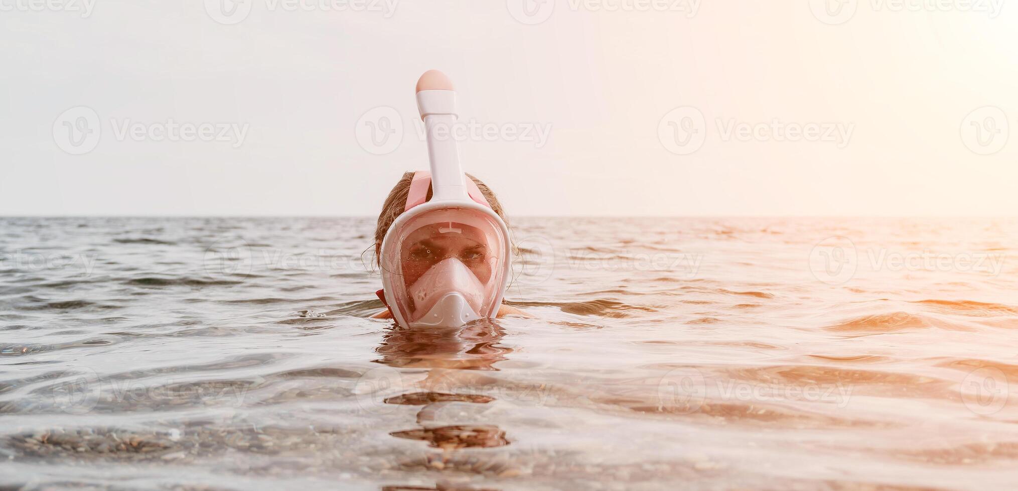Young happy woman in white bikini and wearing pink mask gets ready for sea snorkeling. Positive smiling woman relaxing and enjoying water activities with family summer travel holidays vacation on sea. photo