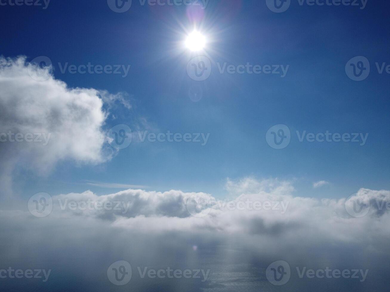 Aerial view. The drone flies over foggy and fluffy clouds. Blue sky sun and sea fog. Abstract aerial nature summer ocean sunset sea and sky background. Vacation, travel and holiday concept photo
