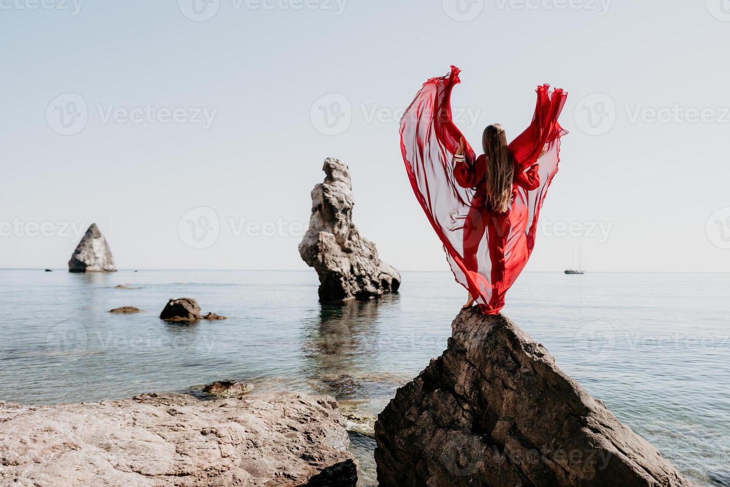 Woman travel sea. Young Happy woman in a long red dress posing on a beach near the sea on background of volcanic rocks, like in Iceland, sharing travel adventure journey photo