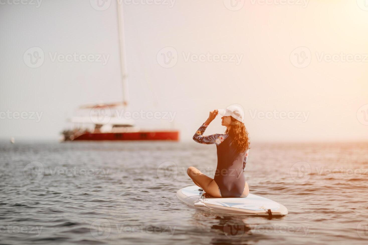 Woman sup yoga. Middle age sporty woman practising yoga pilates on paddle sup surfboard. Female stretching doing workout on sea water. Modern individual female hipster outdoor summer sport activity. photo