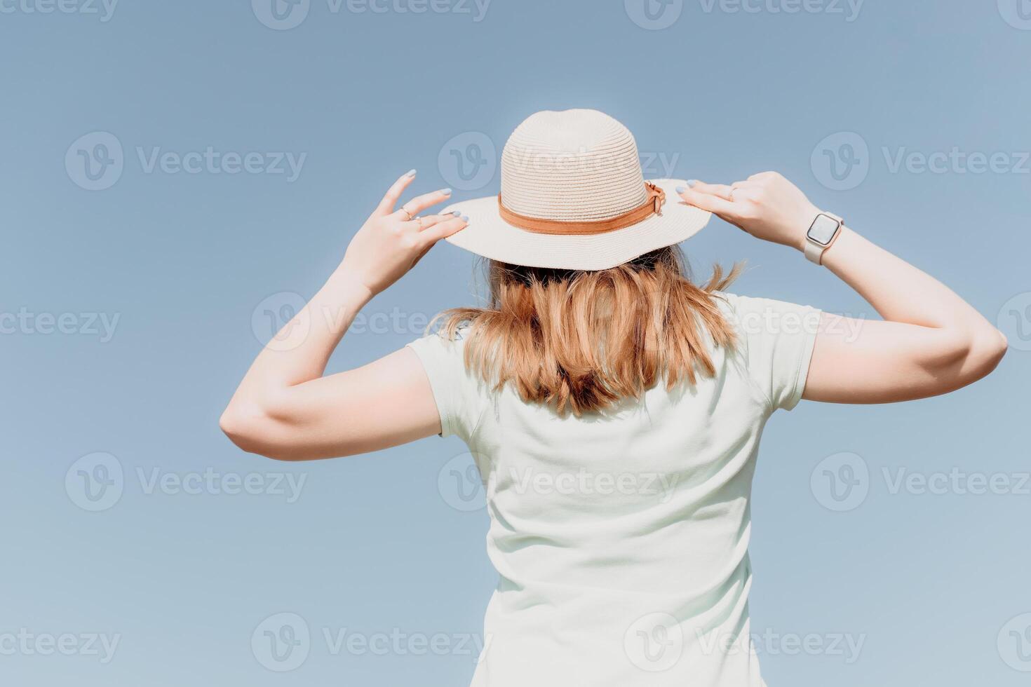 Woman travel sea. Happy tourist in hat enjoy taking picture outdoors for memories. Woman traveler posing on the beach at sea surrounded by volcanic mountains, sharing travel adventure journey photo