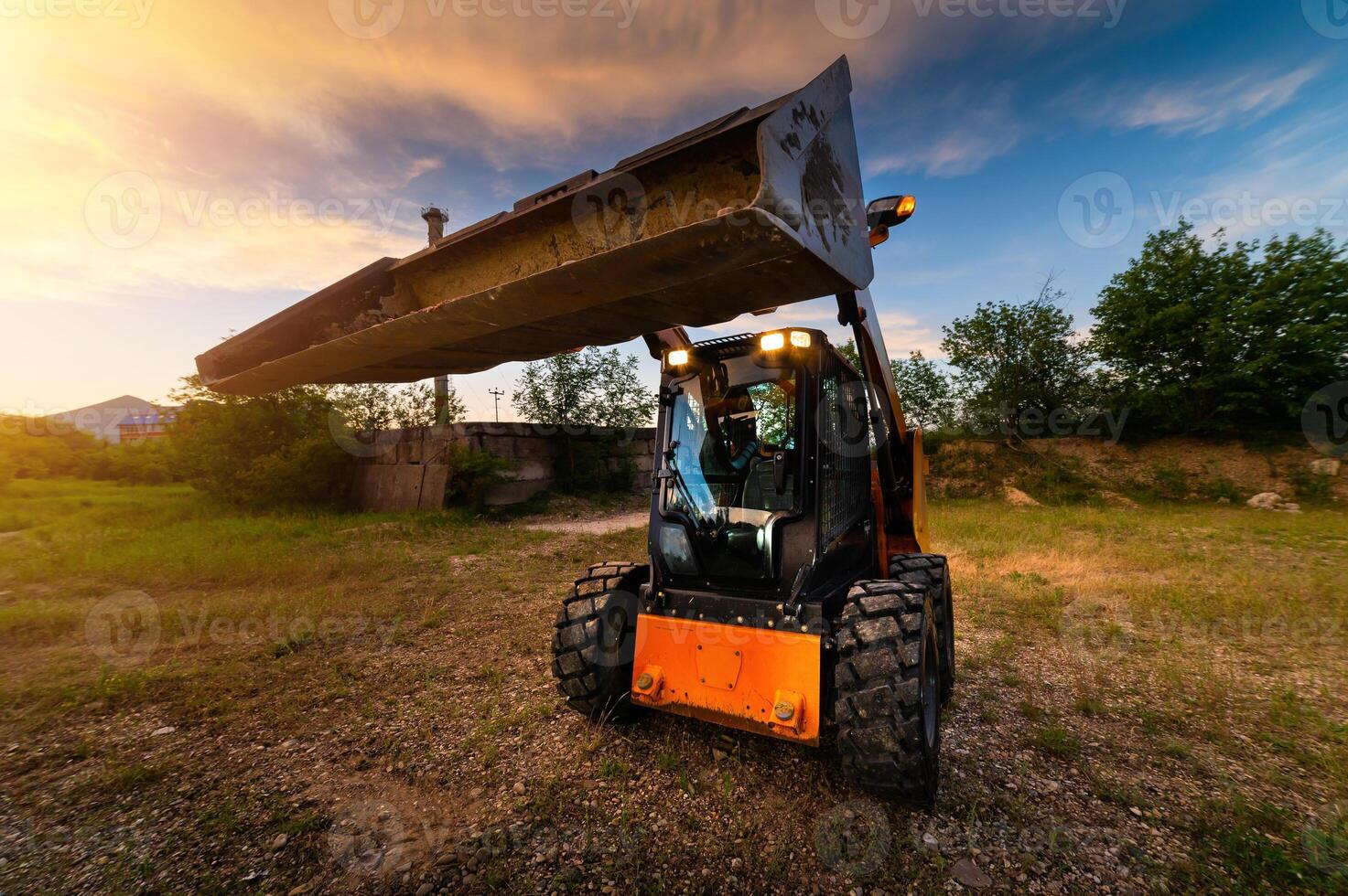 Mini bulldozer, small excavator against the backdrop of the sunset sky in the forest, wide angle photo