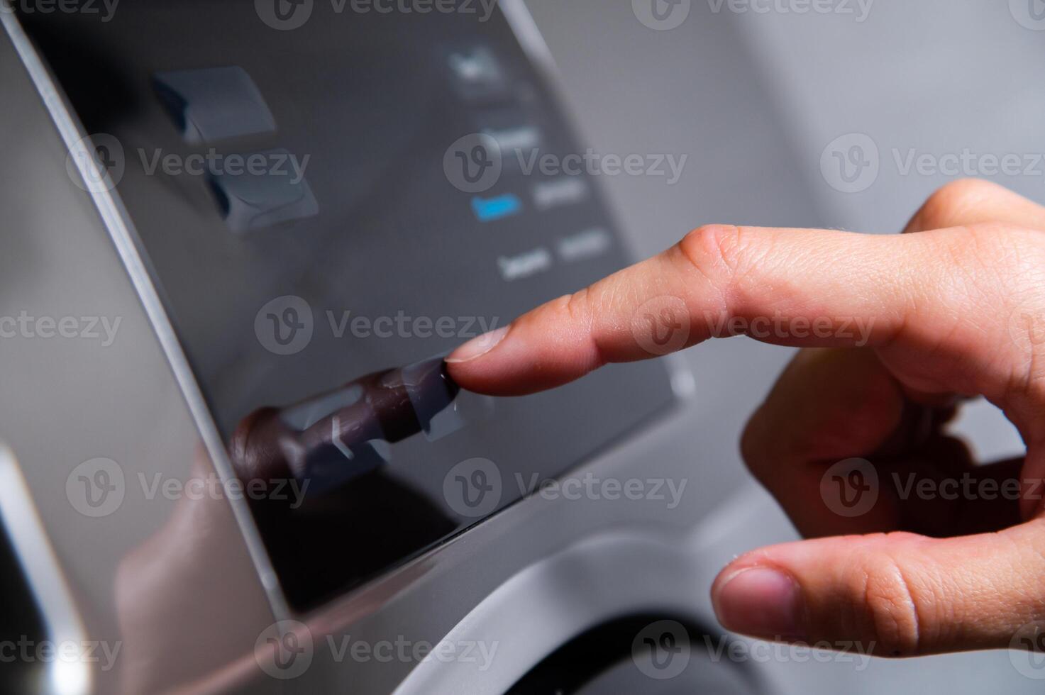 Close-up of a hand selecting a program with a finger while pressing on a washing machine photo