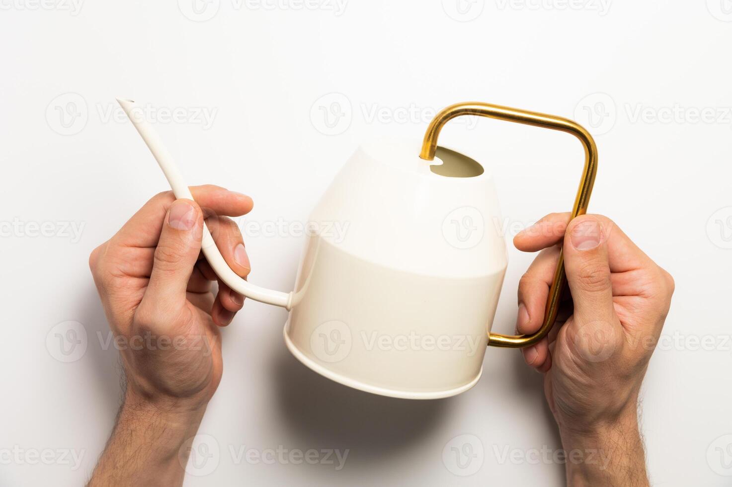 Gardening concept. A man holds a yellow watering can in his hands on a white background, close-up top view photo