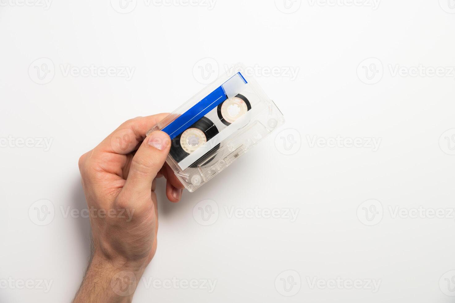 An unrecognizable male hand holds a retro audio cassette on a white background. Using magnetic audio cassettes photo