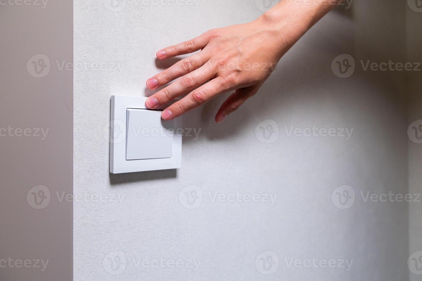 Close-up of a woman's fingers and hand on the light switch at home. Power and energy, energy saving photo