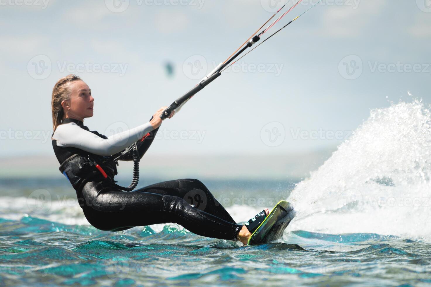 Sexy girl kitesurfing with a kite in the sky in the blue sea, riding the waves with water splashes. Recreational activities, water sports, activities, hobbies and entertainment in the summer photo