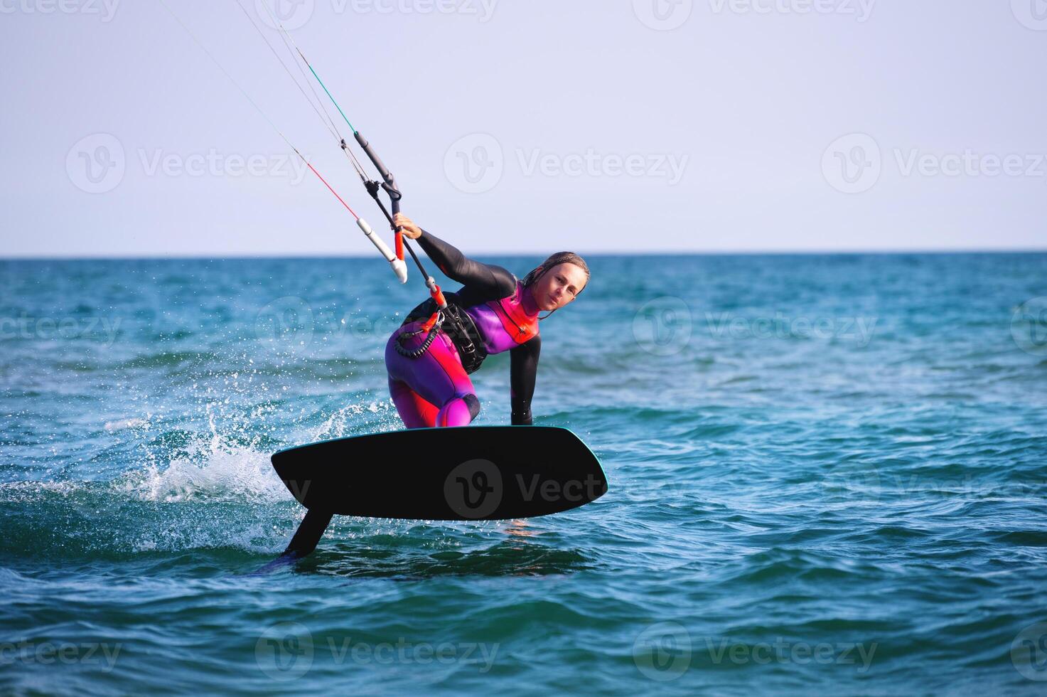 Young Caucasian woman athlete ride on a hydrofoil board with a kite in the open ocean. Hydrofoil is a new direction in kitesurfing photo