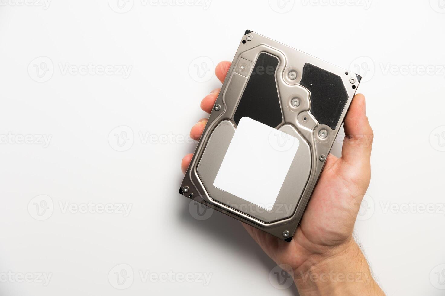a man's hand holds a hard drive from a PC on a white background. Concept of data storage and transmission photo
