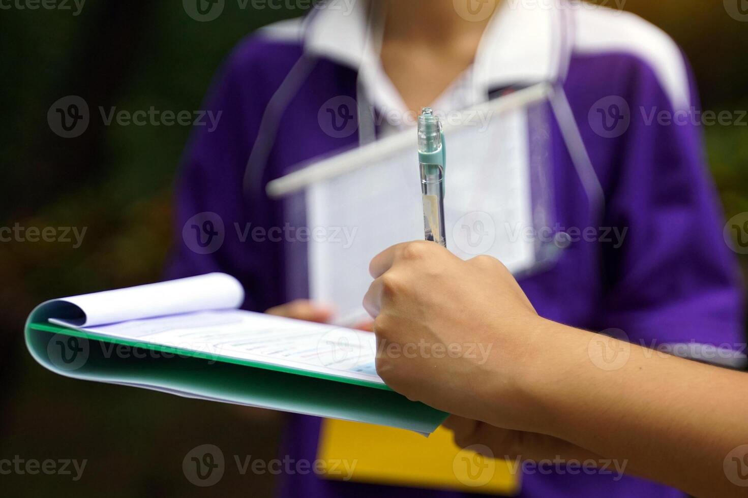 Students write down information about the trees on a document. To study the carbon storage of trees. Soft and selective focus. photo