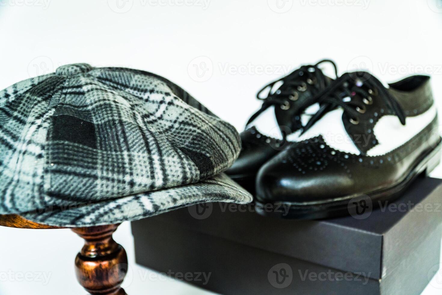Classic studio photo concept of vintage two-tone wingtip shoes in genuine leather with newsboy cap or scaly hat on bronze mannequin on isolated white background