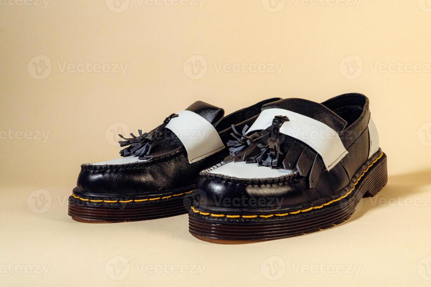 Isolated photo of an elegant and shiny two-tone vintage shoe product on a beige background. Close up of black and white tassel shoes with rubber outsole made from genuine cowhide.