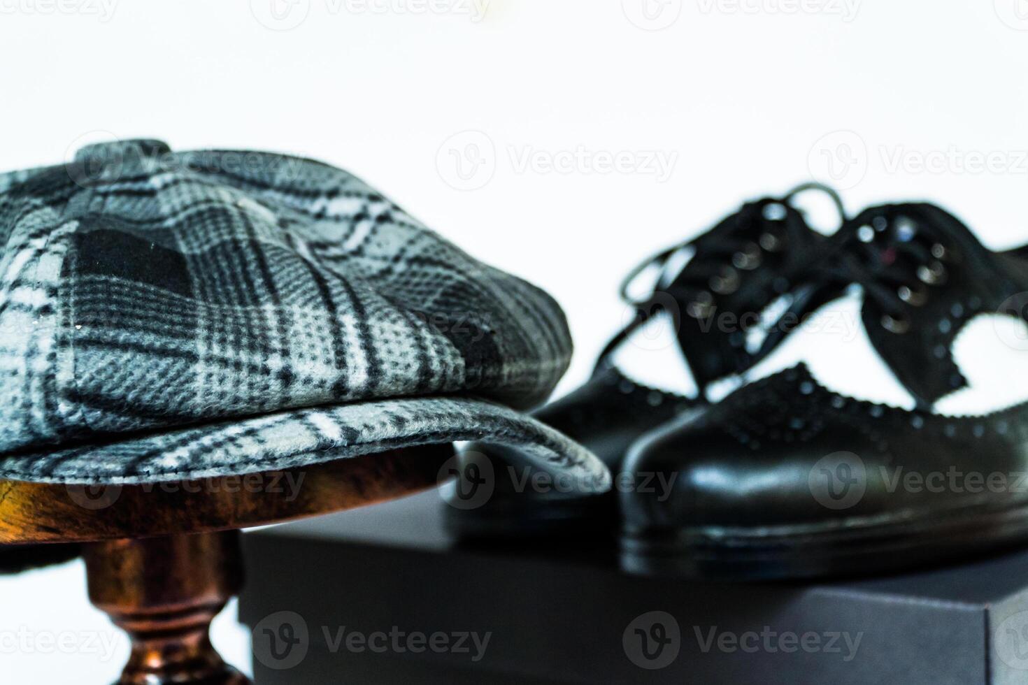 Classic studio photo concept of vintage two-tone wingtip shoes in genuine leather with newsboy cap or scaly hat on bronze mannequin on isolated white background