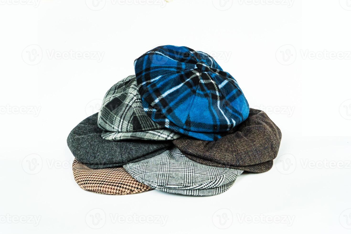 Stack of classic wool newsboy caps in different colors and patterns on a white background. Classic hats that were popular in the 50s are stacked for photos in the catalogue