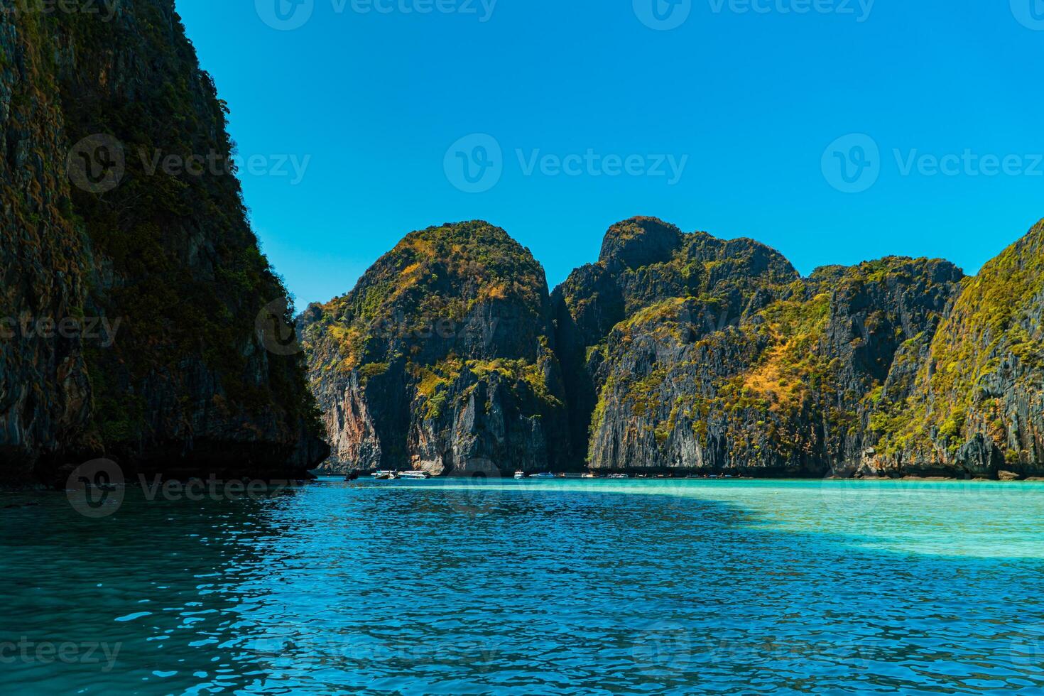 Beautiful natural view of Maya Bay during the day. Popular tourist destination on Phi-phi Island, Thailand during high season with clear sea water, white sand and very iconic high cliffs photo