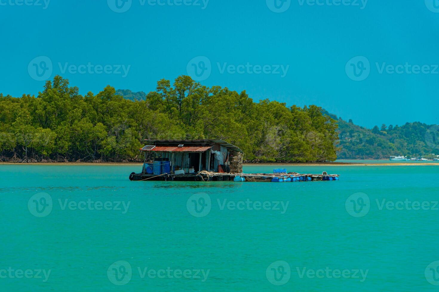 Small floating houses between the horizon line that separates the sea from the sky and set against a backdrop of plains and mountains. Floating houses used by fishermen as a place to cultivate fish photo