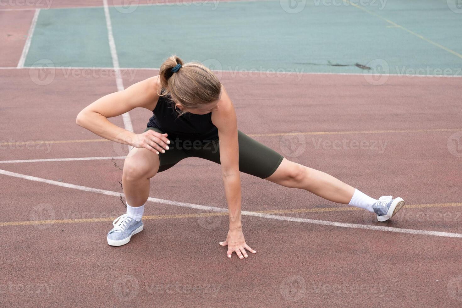 Caucasian sportive female boxer training at the stadium, warming up and stretching photo