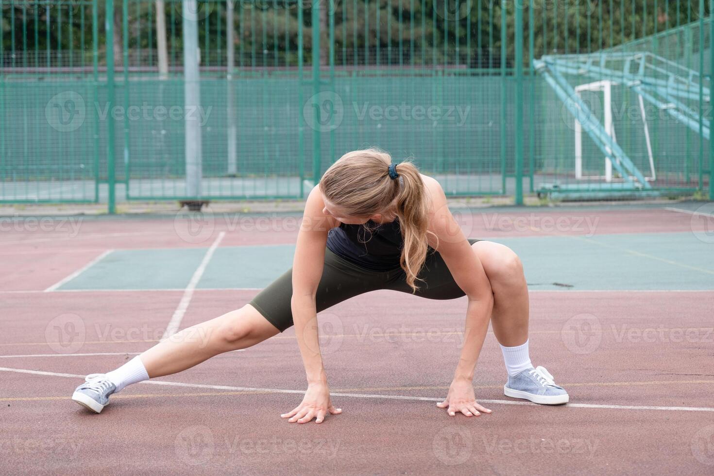Caucasian sportive female boxer training at the stadium, warming up and stretching photo