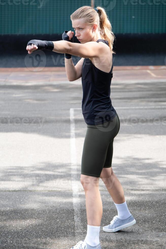 young female boxer training urban gray wall background photo