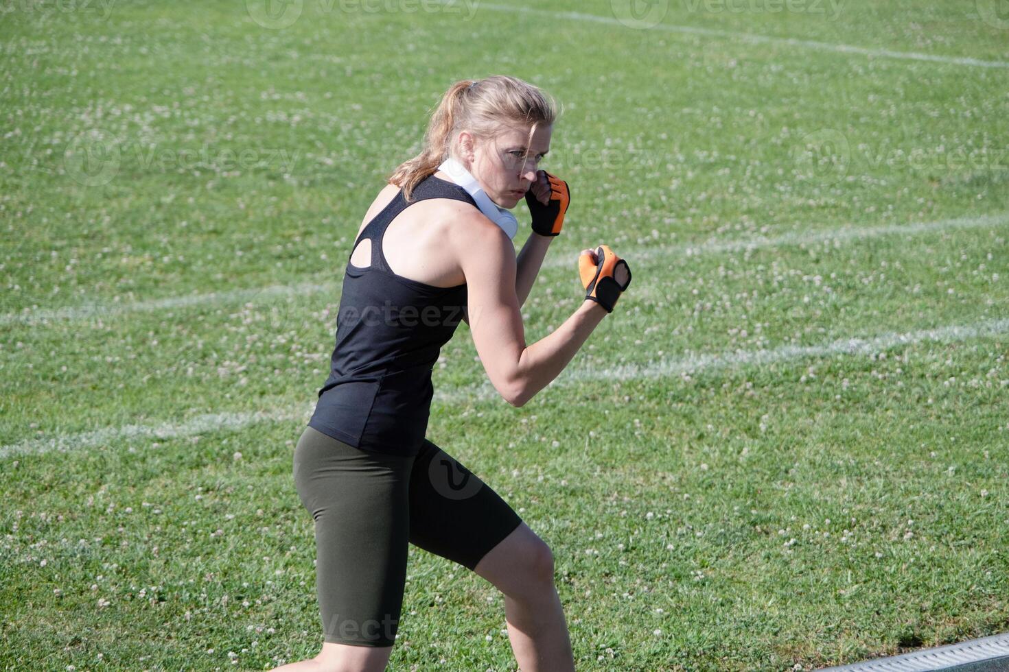 young female boxer training in the stadium standing in position photo
