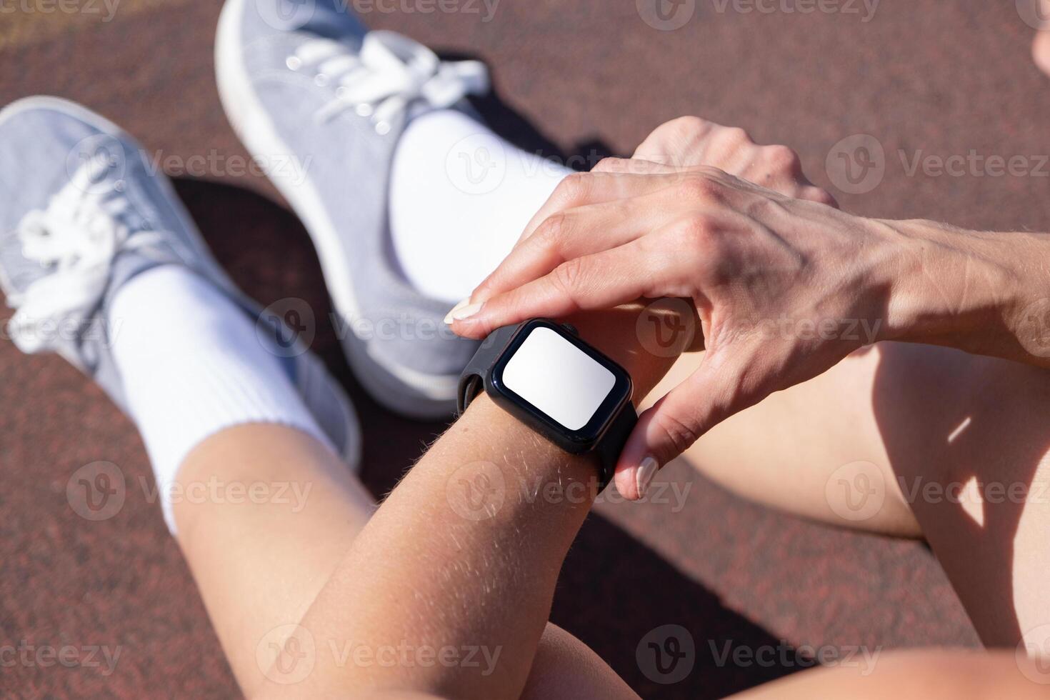 View from above of athlete checking mobile app on his wristwatch, taking pulse or heart rate after heavy workout outdoor. smartwatch screen mockup photo