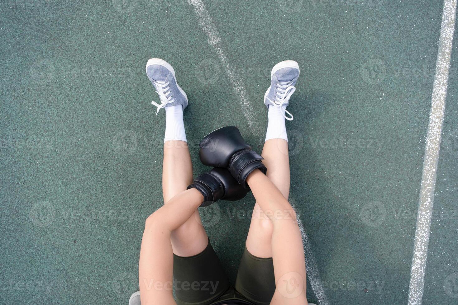 young female boxer training in the stadium, having rest sitting photo