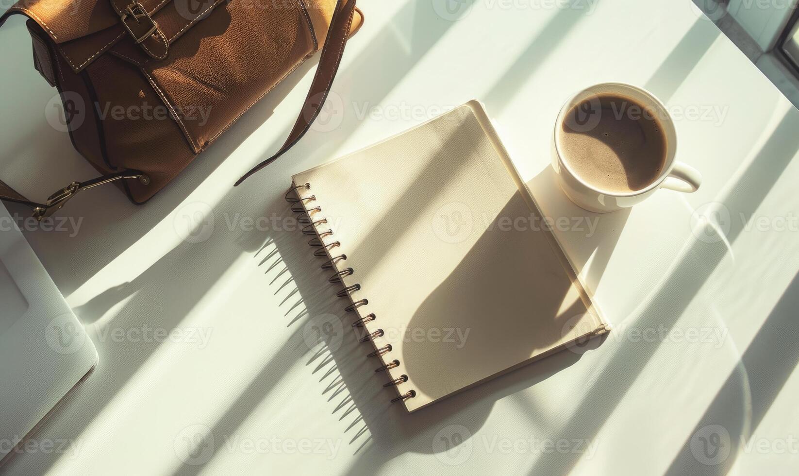 Closed notebook on a white table with a cup of coffee and a handbag photo