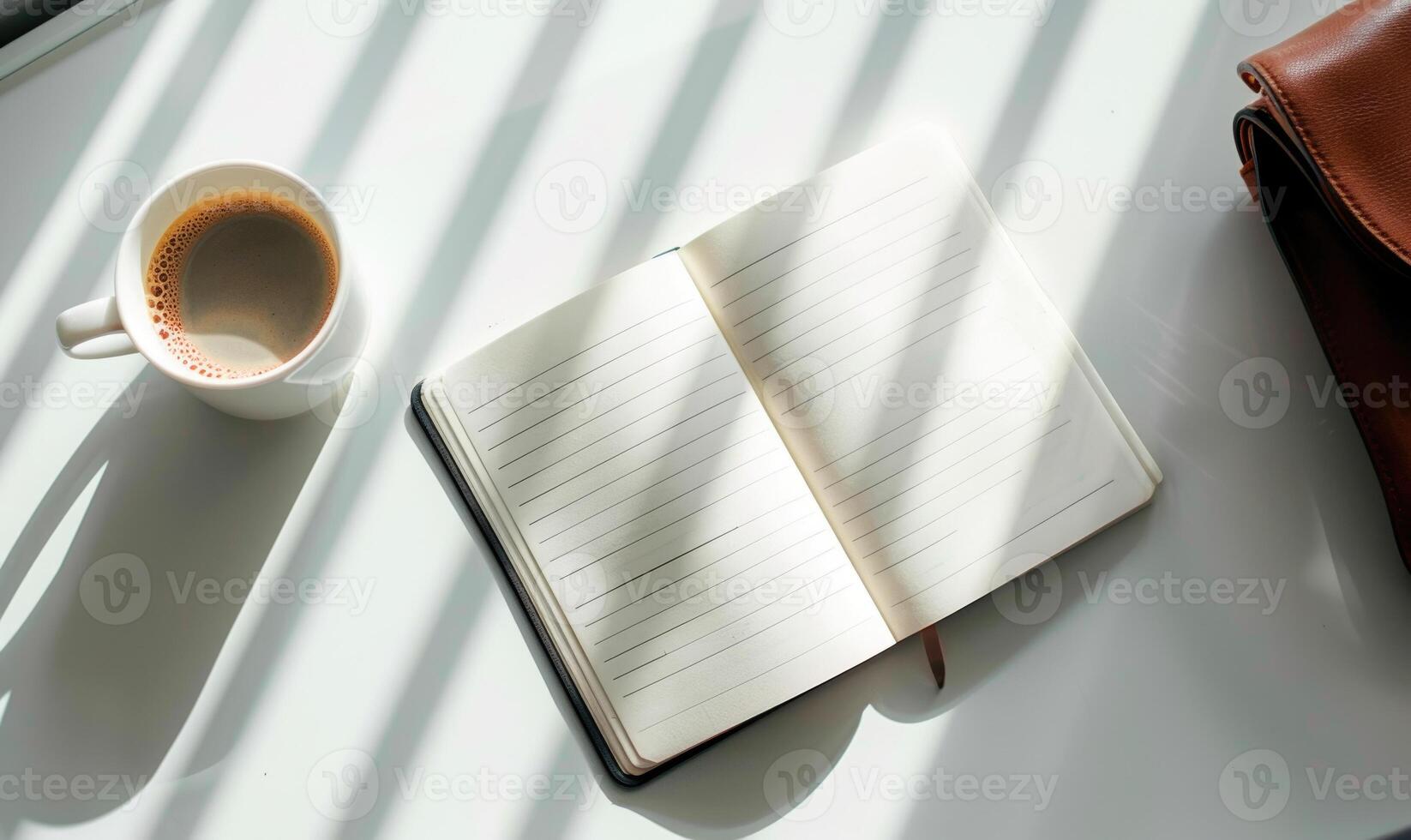 Closed notebook on a white table with a cup of coffee and a handbag photo