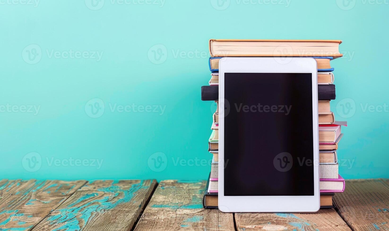 Stack of books on a wooden table with a pastel periwinkle background with a digital tablet photo