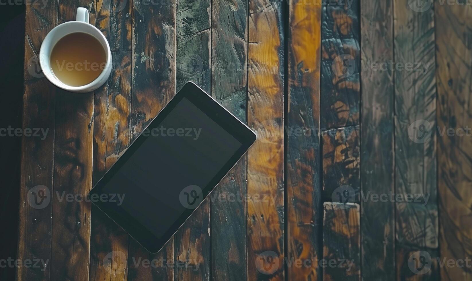 Tablet on a wooden table with a cup of coffee on the left photo