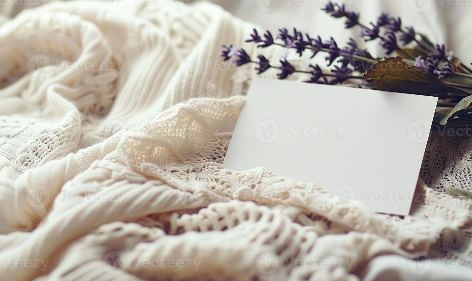 White blank card in a delicate lace frame on a pastel butter yellow table, with a knitted cloth and a small lavender bunch photo