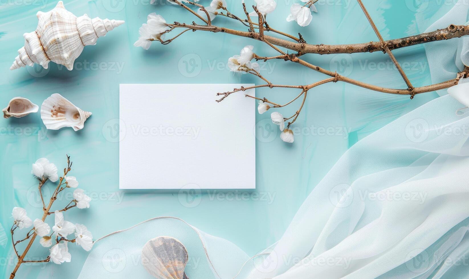 White blank card on a pastel turquoise background, with a seashell and a piece of driftwood photo