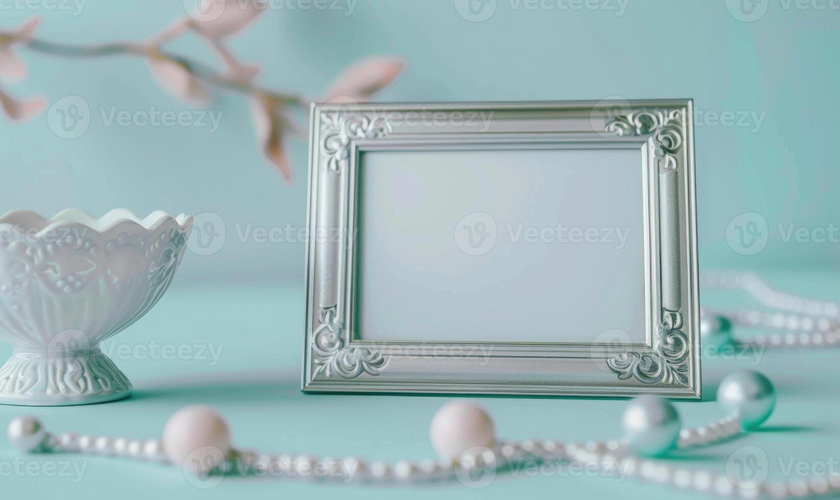 White blank card in a silver frame on a pastel sky blue table, with a white ceramic bowl and pastel colored beads photo