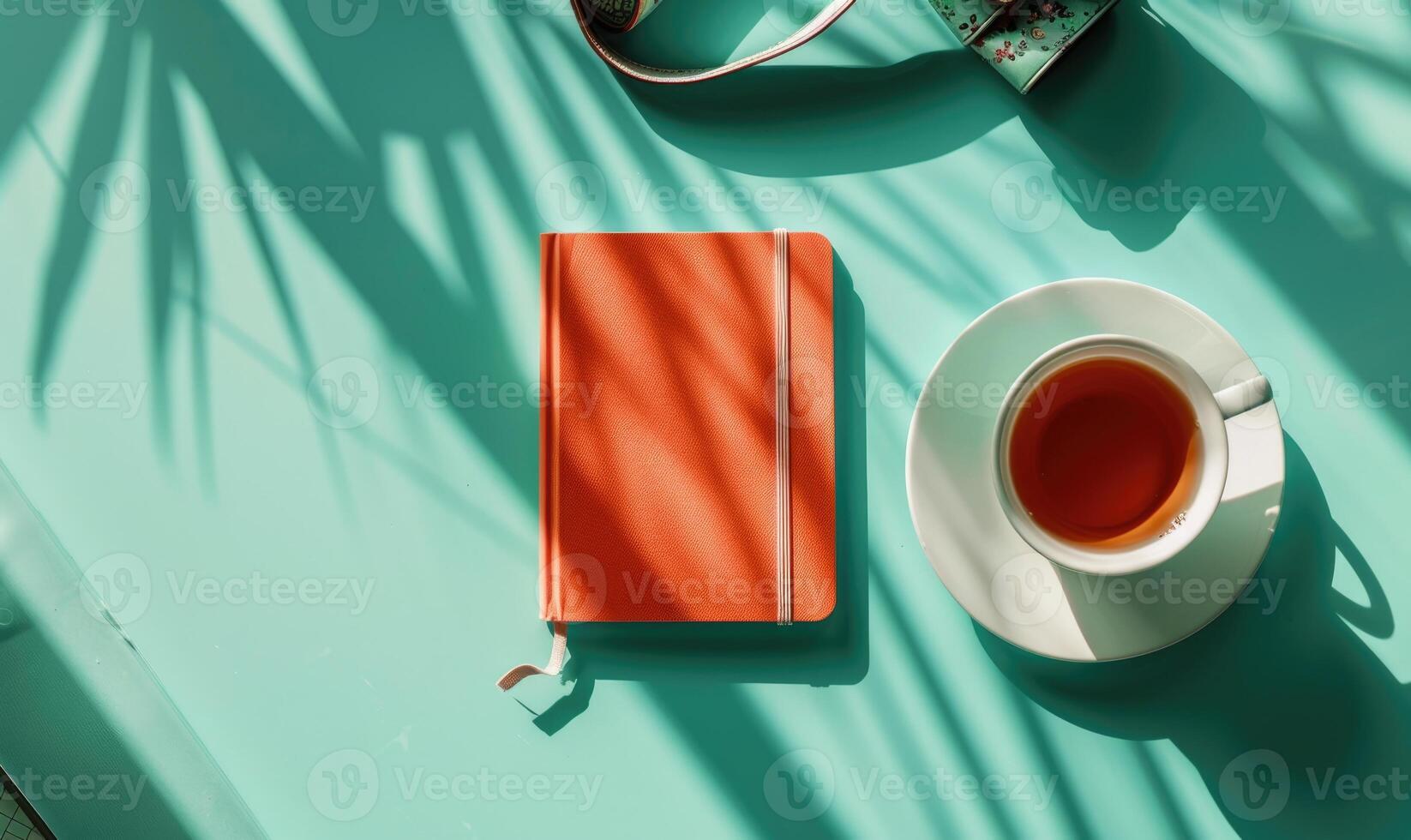 Closed notebook on a light blue table with a cup of tea photo