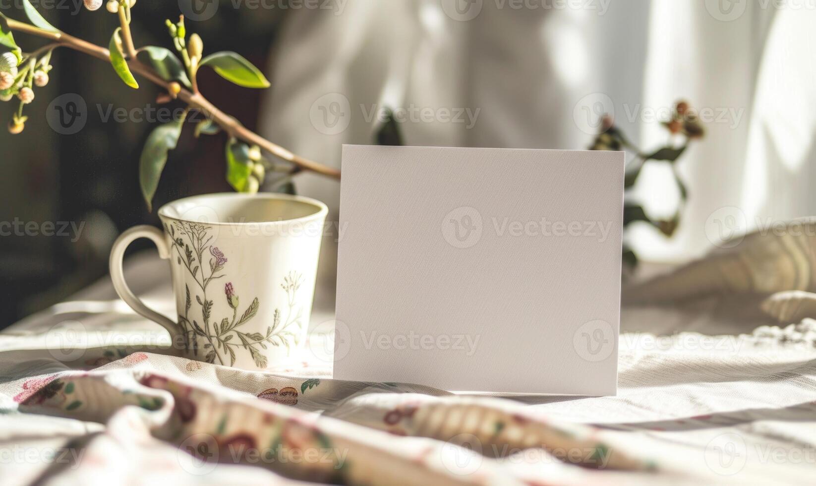 White blank card on a pastel ivory table, with a ceramic mug and a floral print napkin photo