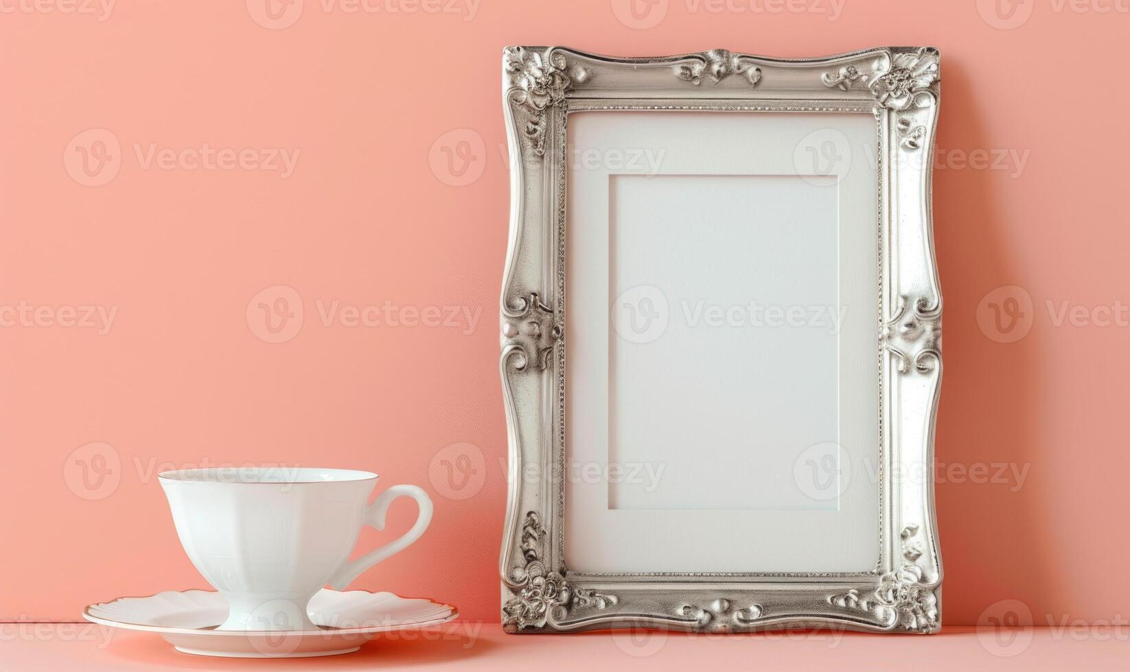 White blank card in a vintage silver frame on a pastel peach background, with a vintage tea cup photo