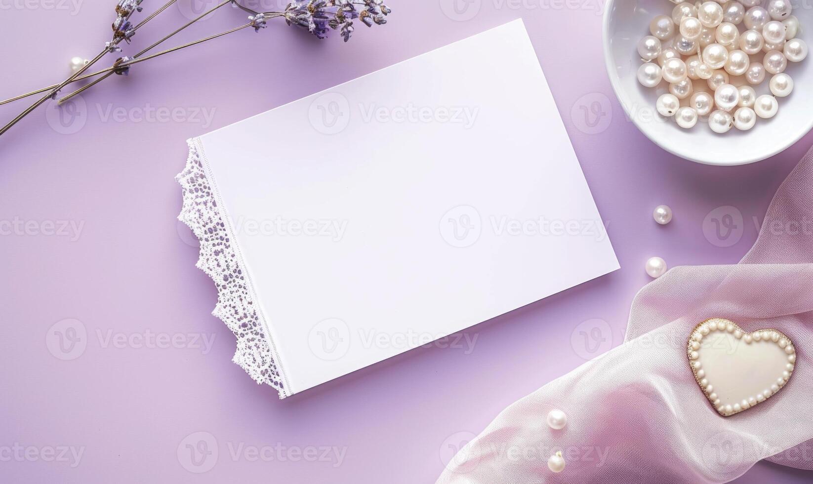 White blank card on a pastel lavender background, with a silk scarf and a pearl necklace photo