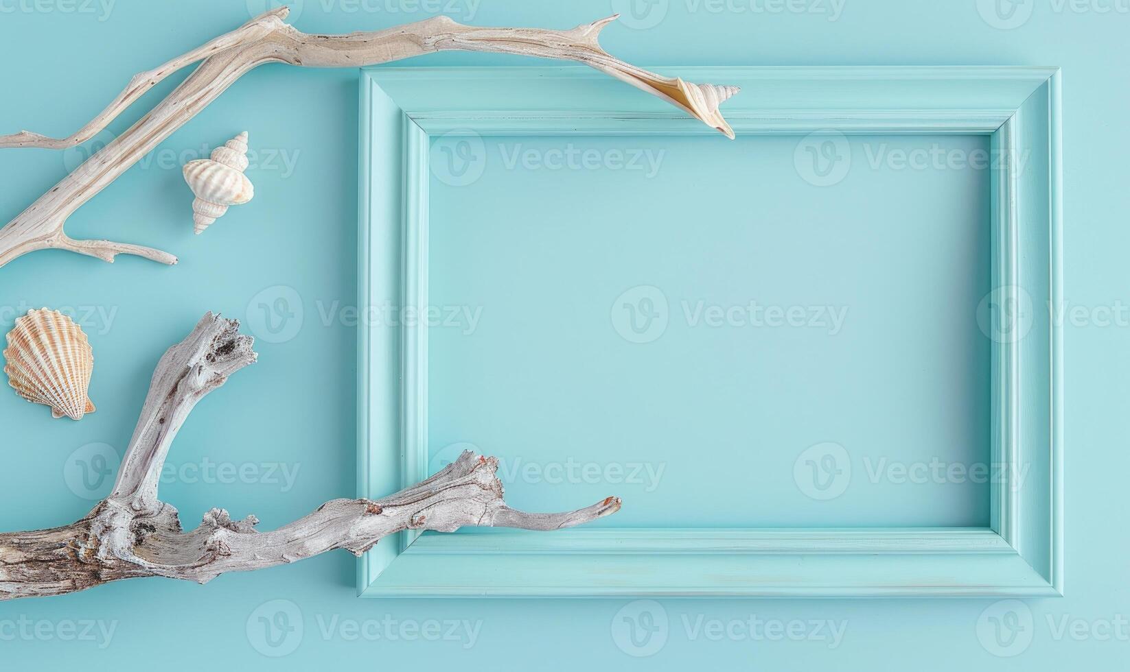 White blank card in a turquoise frame on a pastel turquoise background, with a seashell and a piece of driftwood photo