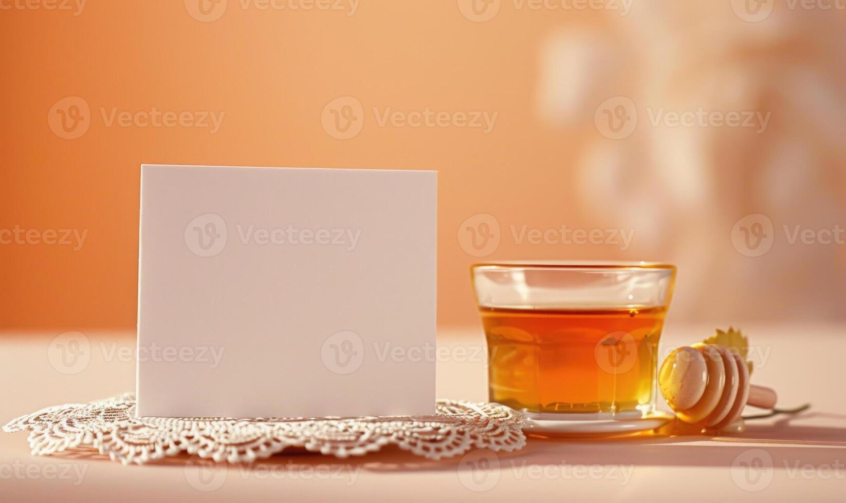 White blank card on a pastel peach table, with a delicate lace doily and a small glass jar of honey photo