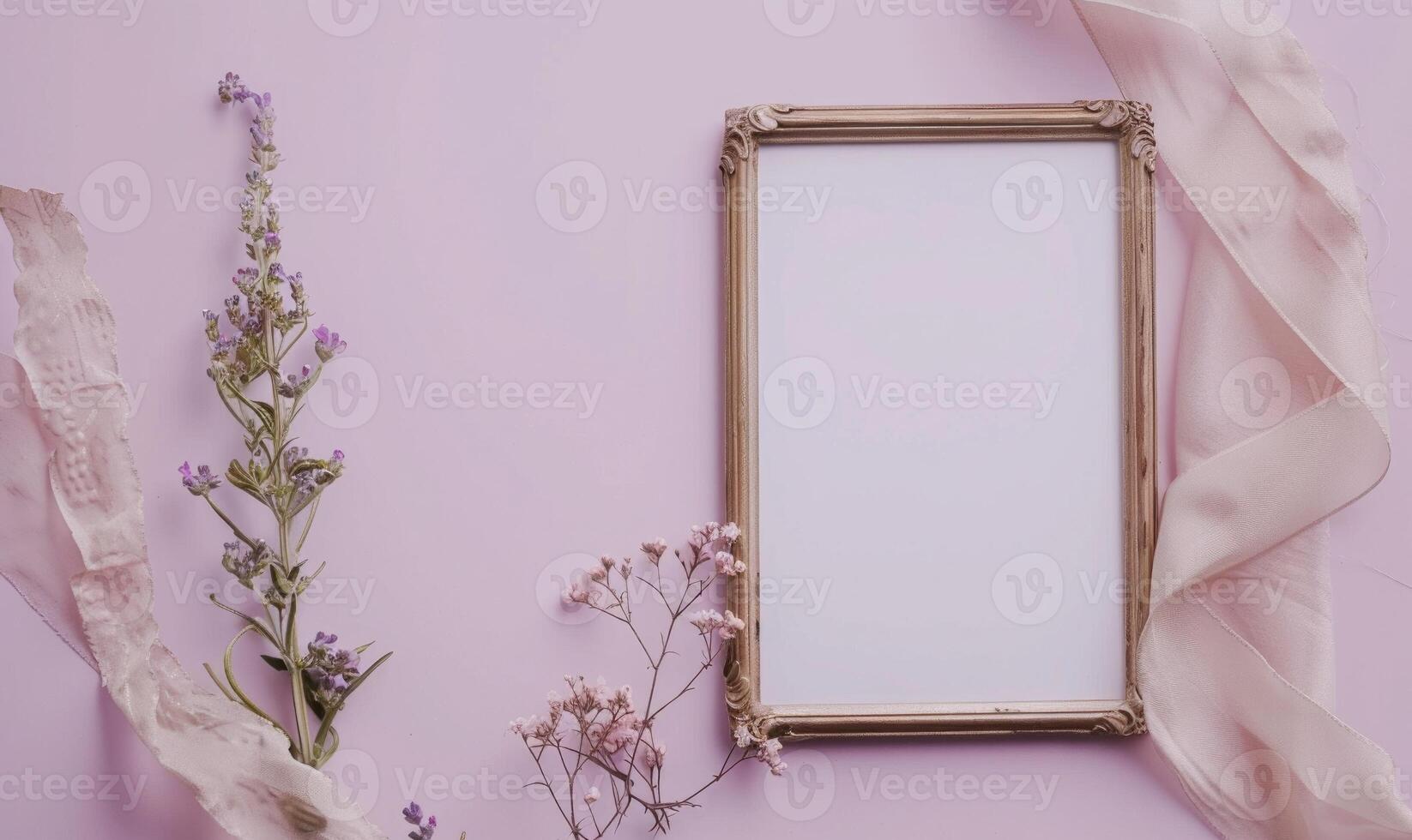 White blank card in a vintage bronze frame on a pastel lilac background, with a small bunch of wildflowers and a ribbon photo