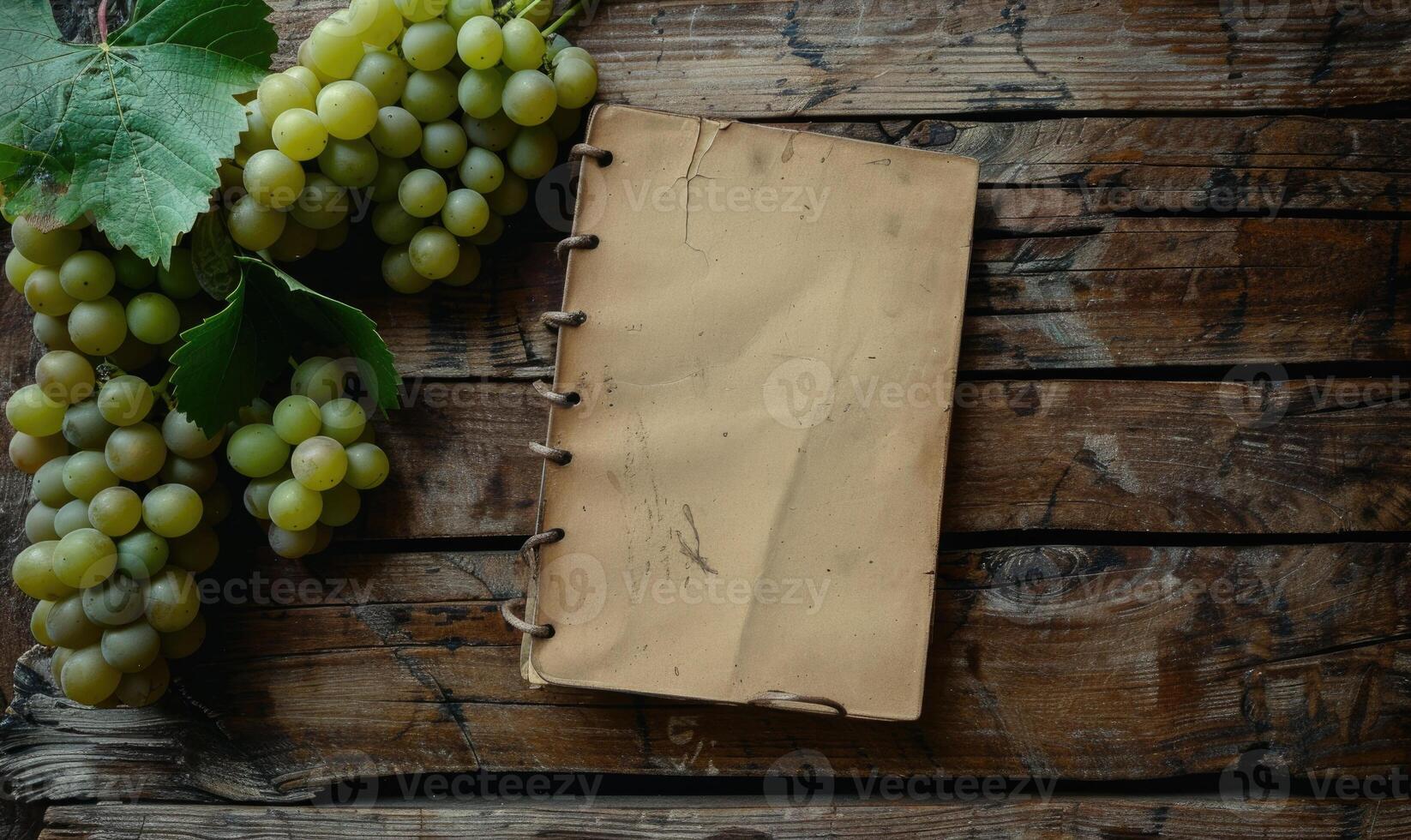 Notebook on a wooden table with a bunch of grapes photo