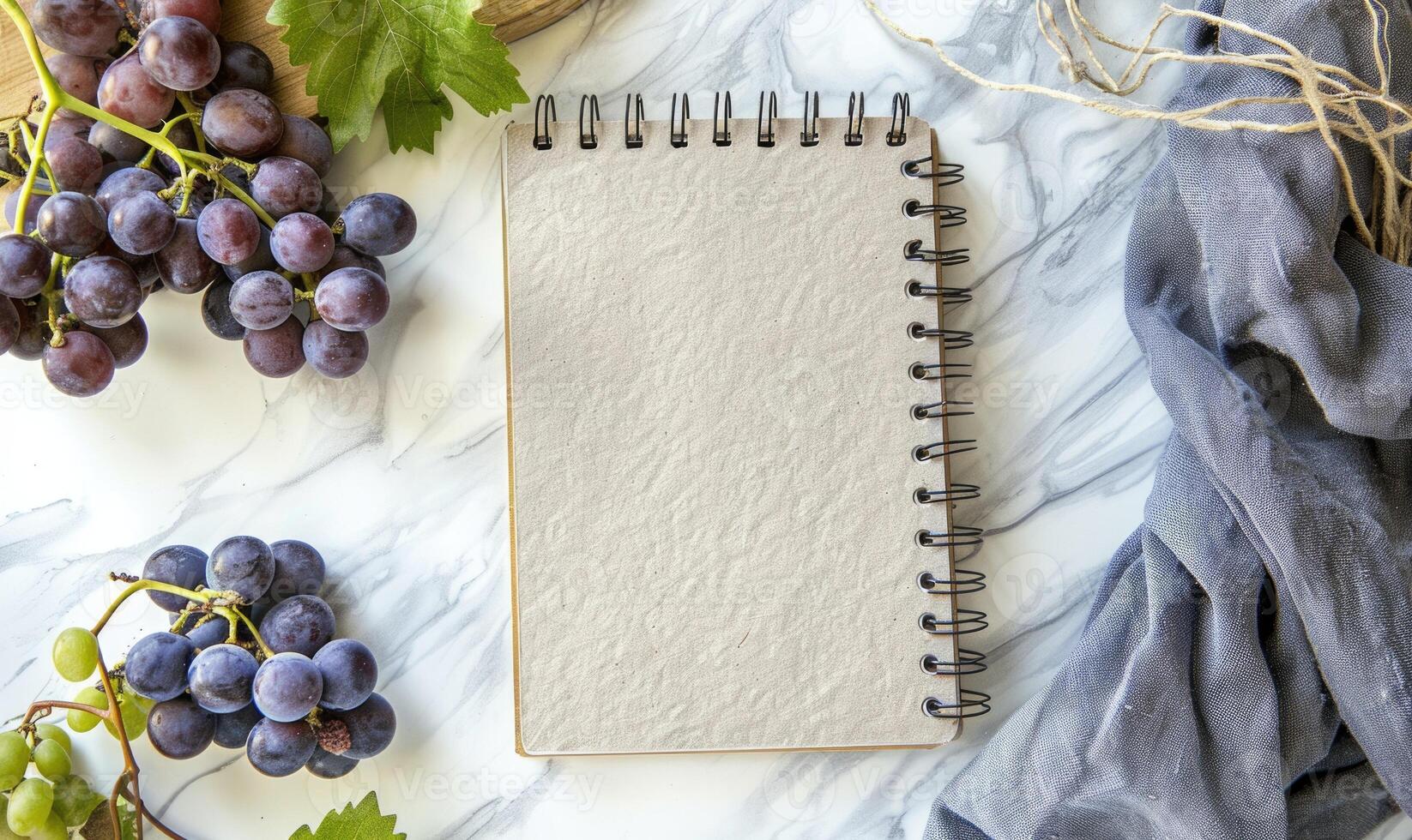 Closed notebook on a white table with a bunch of grapes photo