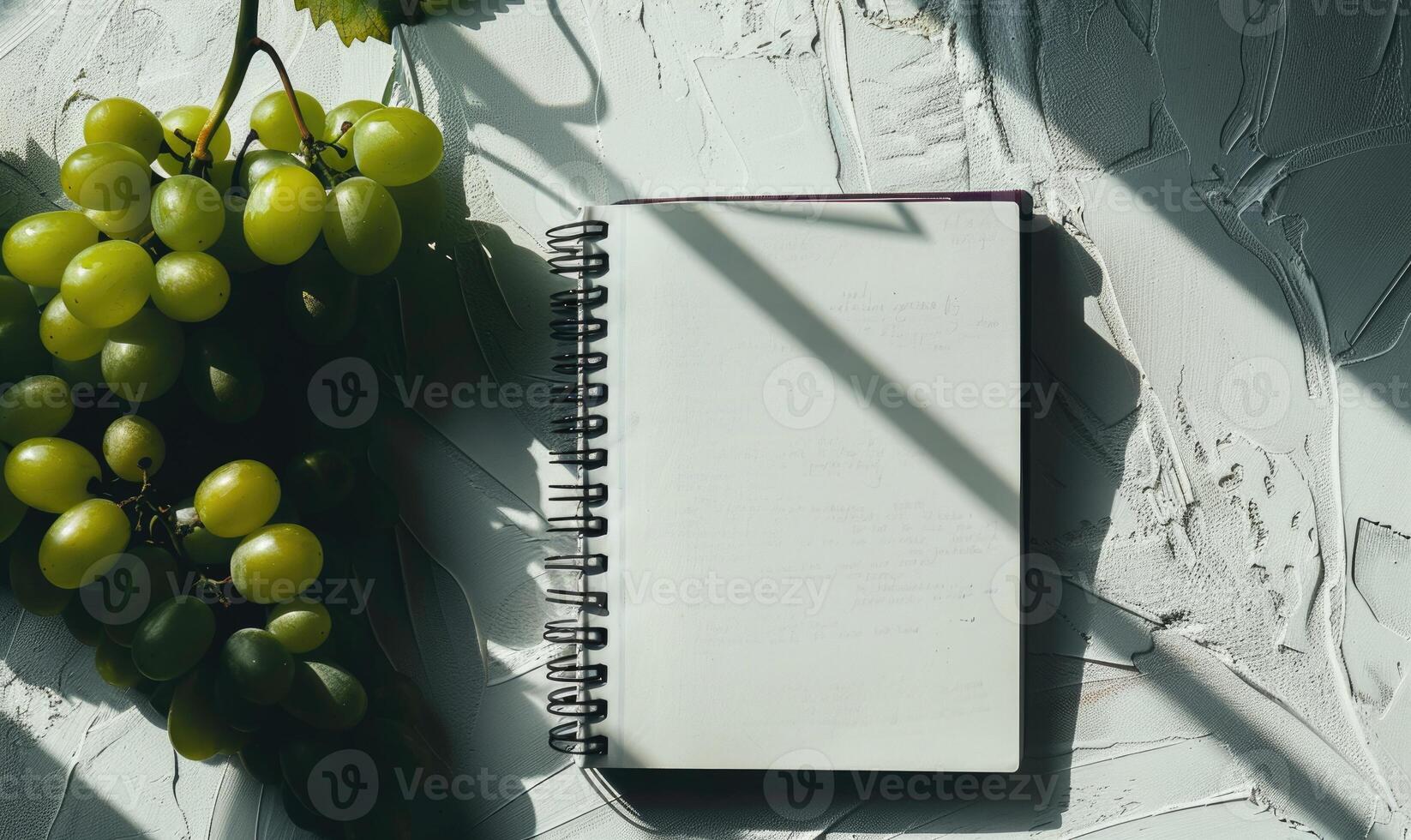 Closed notebook on a white table with a bunch of grapes photo