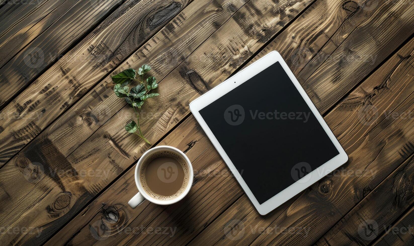 Tablet on a wooden table with a cup of coffee on the left photo