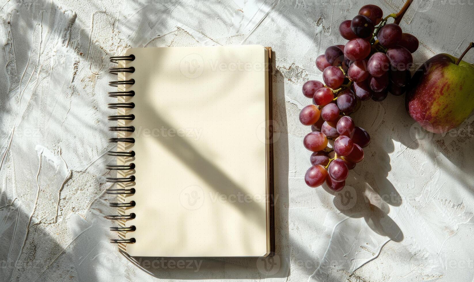 Closed notebook on a white table with a bunch of grapes photo