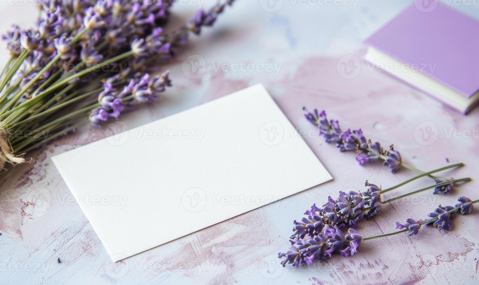 White blank card on a pastel periwinkle table, with a sprig of lavender and a small notebook photo
