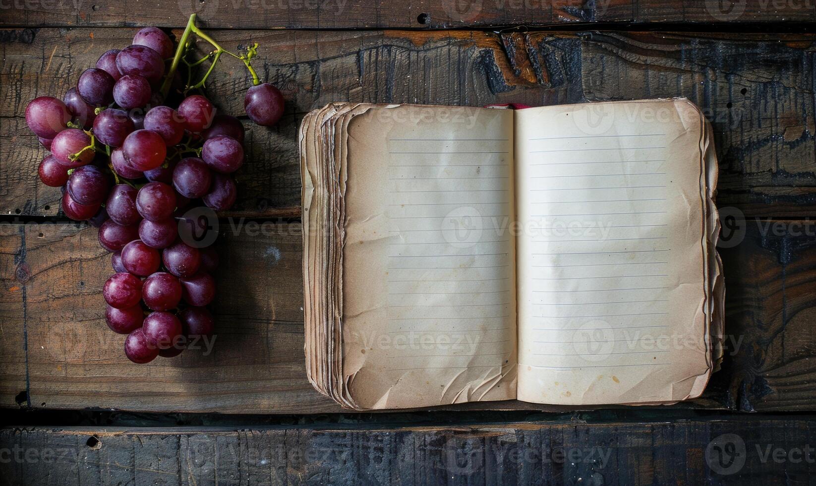 Notebook on a wooden table with a bunch of grapes photo