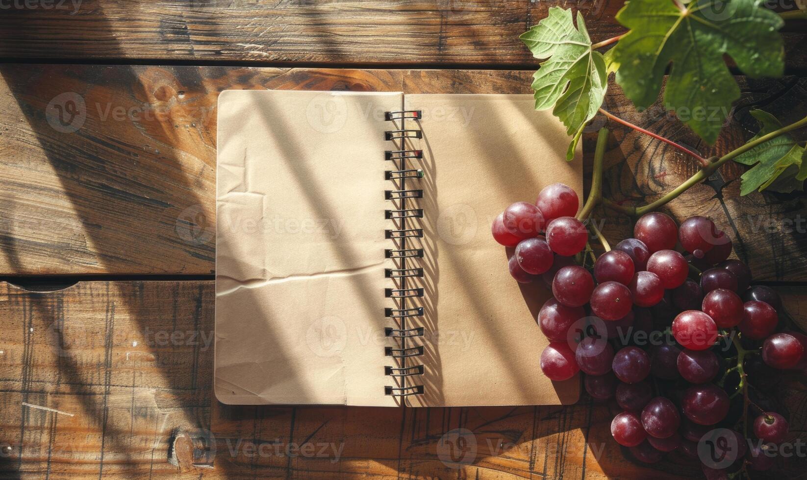 Notebook on a wooden table with a bunch of grapes photo