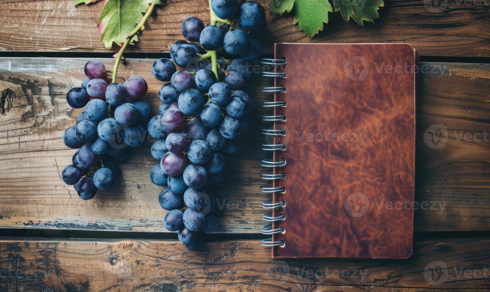 Notebook on a wooden table with a bunch of grapes photo